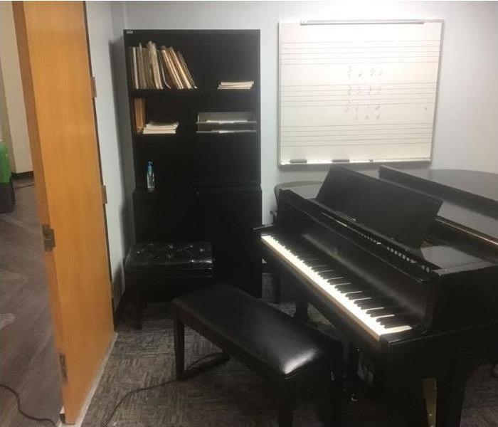 A black piano sits in a storage room