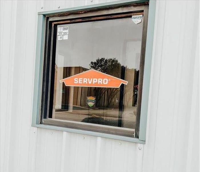 Orange SERVPRO logo and Certified: SERVPRO Cleaned sticker on the window of a warehouse building.