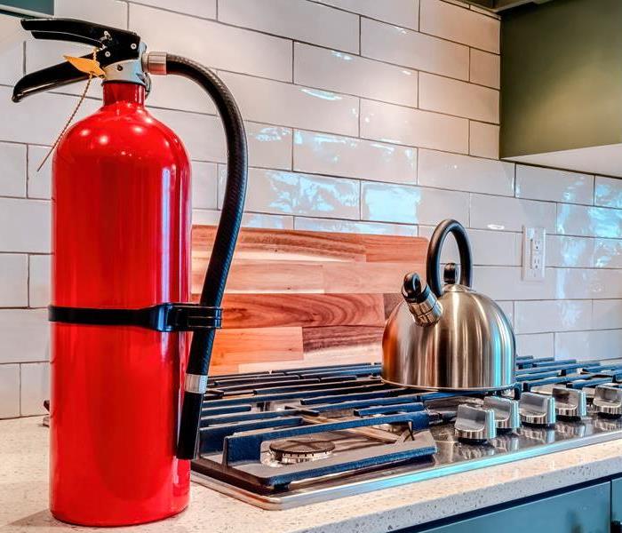 A red fire extinguisher sits on a kitchen counter
